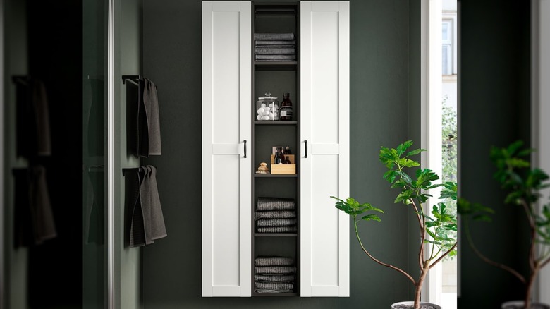 The ENHET storage combination in a bathroom next to hanging towels with more towels and other bathroom products in the shelves in the center