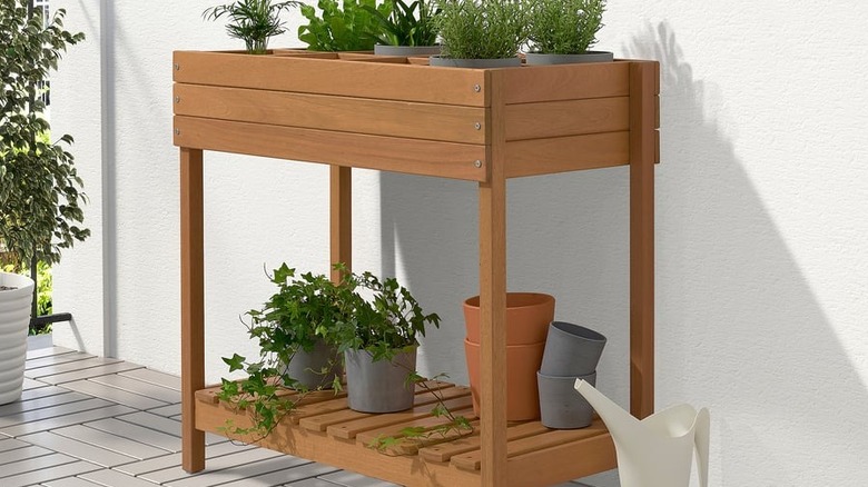 The HATTHOLMEN plant stand filled with plants above with extra pots and plants on the bottom