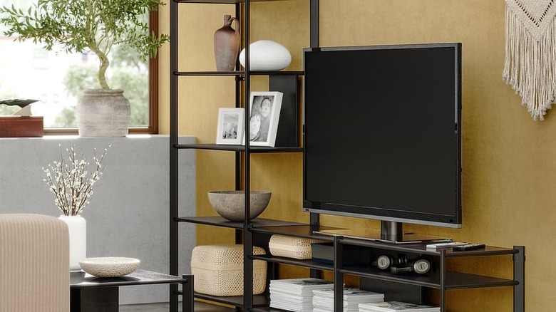 A TV on the open-shelved JÄTTESTA TV storage combination with decorations on every shelf