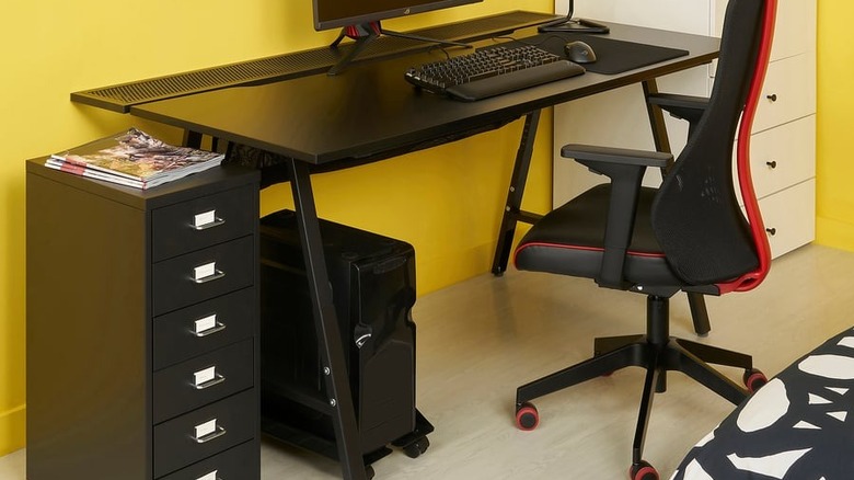 The UTESPELARE / MATCHSPEL gaming desk, chair and drawer unit set up in a room with a gaming chair and a computer