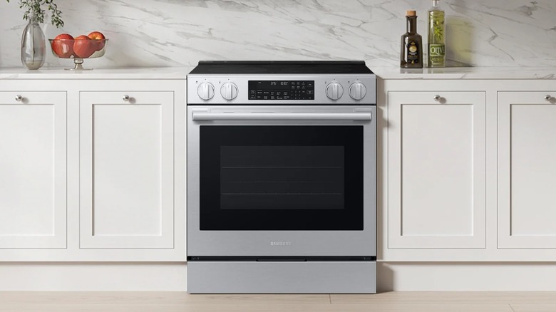 The Samsung Bespoke Smart Slide-in Electric Range with white counters and a marble backsplash