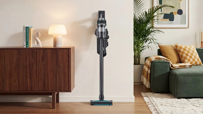 The teal green Samsung Jet 85S Stick Vac in a hallway with a green couch in the background