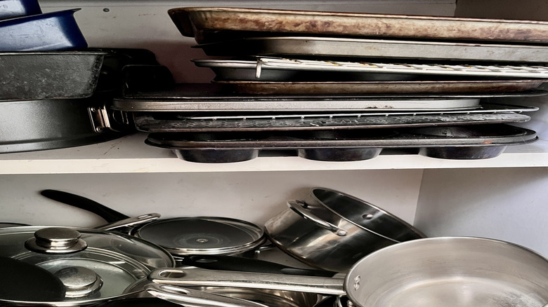 piles of bakeware in cabinet