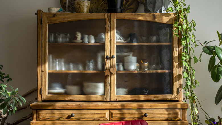 A large wooden china cabinet with frosted glass.
