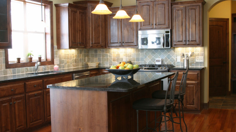 A rustic modern kitchen with dark cabinets and countertops.