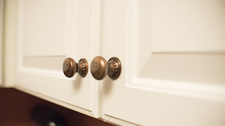 A close up on two vintage cabinet knobs with patina.