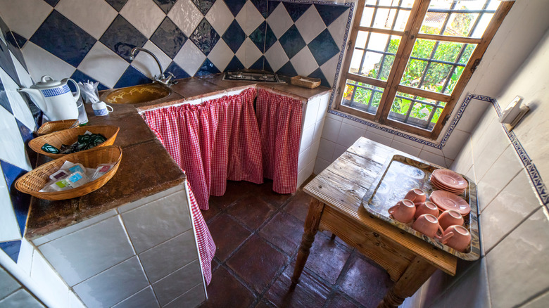 A small rustic kitchen with gingham skirt curtains.