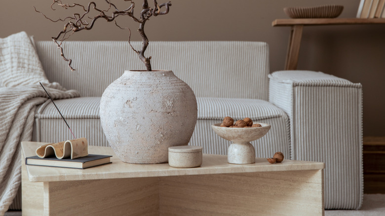 Rough stone bowl and vase with walnuts and tree styled on coffee table