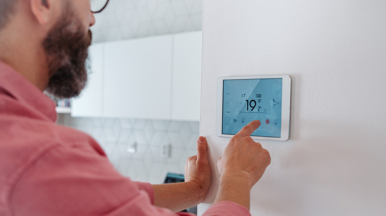 A person adjusts a smart thermostat