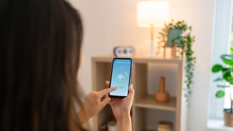 A person controls the lighting level using a smart phone app