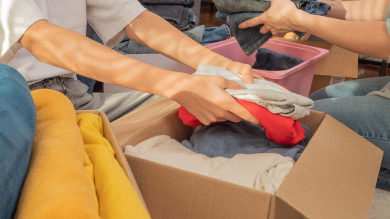 People sorting cardboard boxes filled with clothes