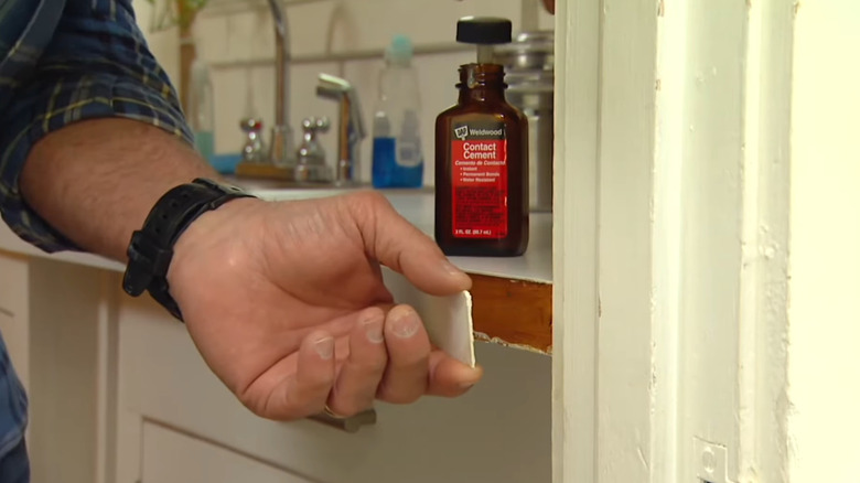 A man uses a bottle of contact cement to fix laminate countertops