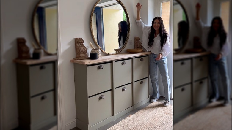 A woman poses with a faux built-in she made from IKEA cabinets.