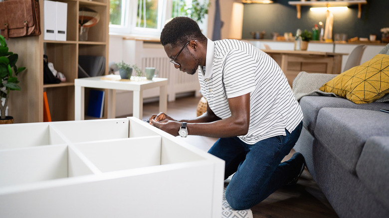 A man assembles a piece of IKEA furniture