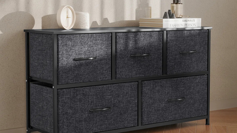 A gray fabric dresser with decor on top