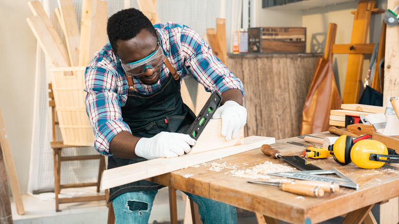 a carpenter using a level at woodworking worktable