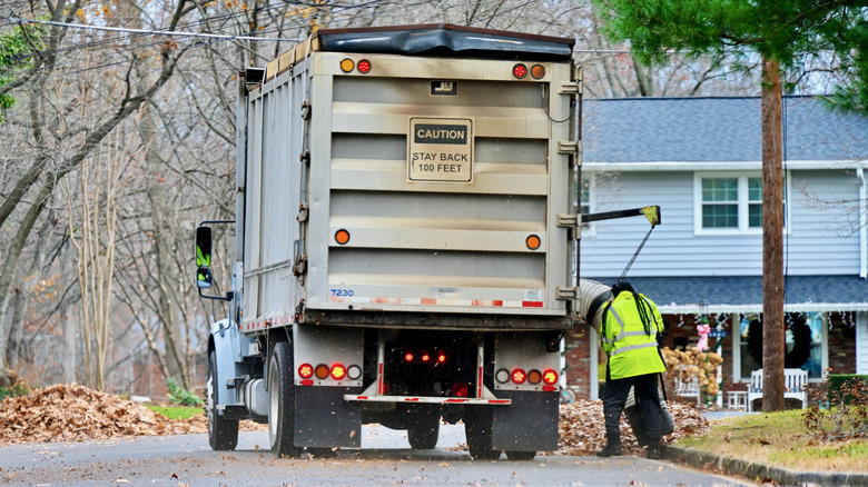 Leaf collection truck with worker suctioning leaves