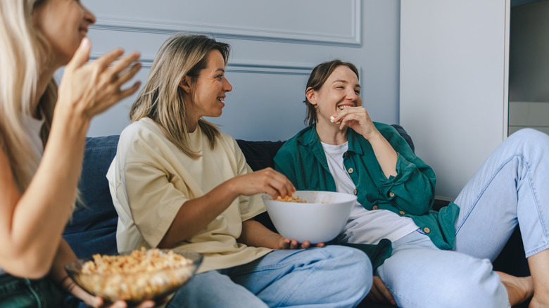 Friends smiling and lounging casually with snacks