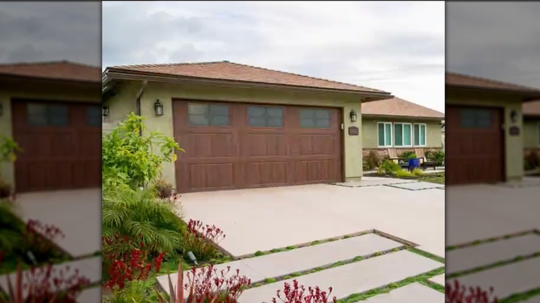 A DIY concrete driveway with various sized slabs and plants.