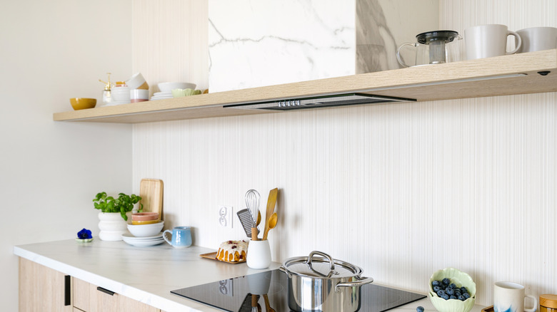 A kitchen scene showing an extractor hood with a marble stone surround