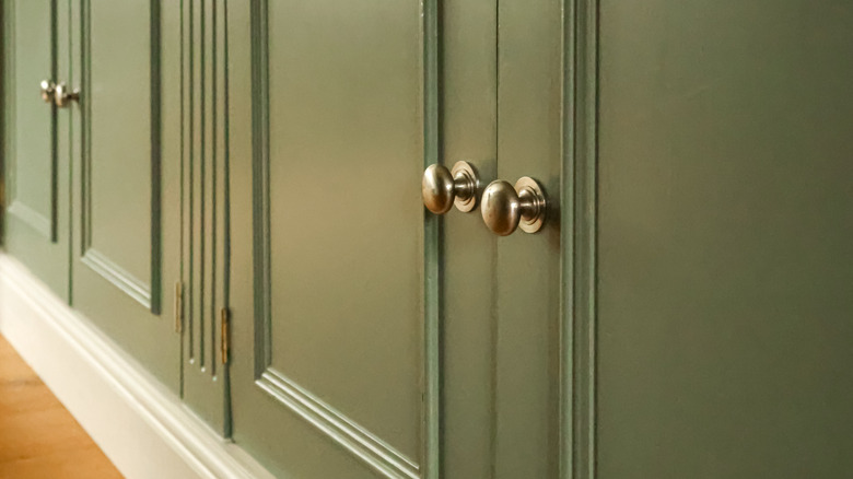 Beautiful sage green kitchen cabinets with decorative molding, plus a custom matching vent panel