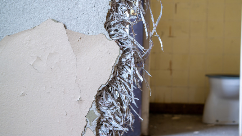 An old wall in an apartment with an asbestos filling