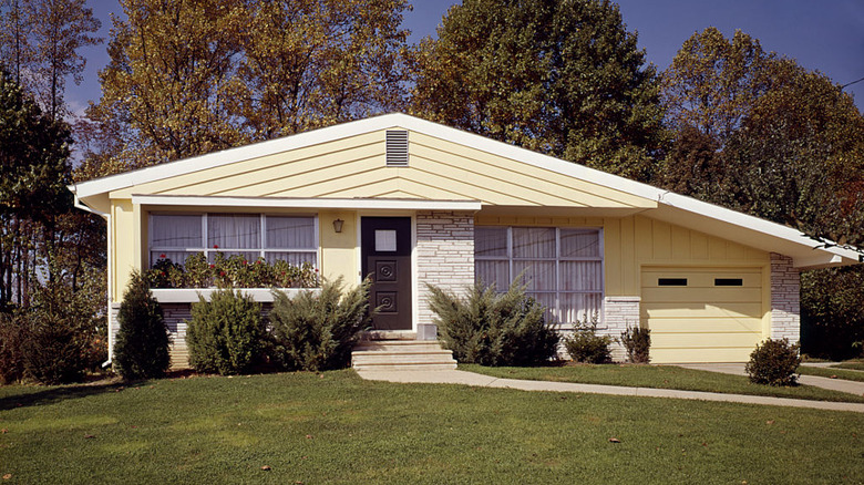 A yellow mid-century house with a matching garage