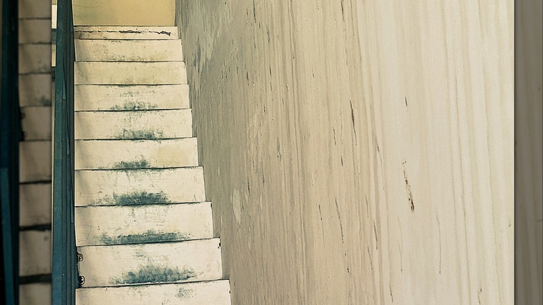 A dirty narrow staircase with inconsistent step heights