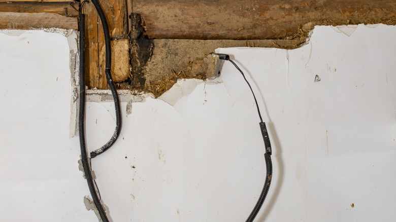 An exposed electric wire hanging from a wall