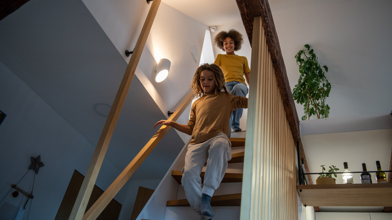Kids running down a narrow staircase with inconsistent steps and an open railing