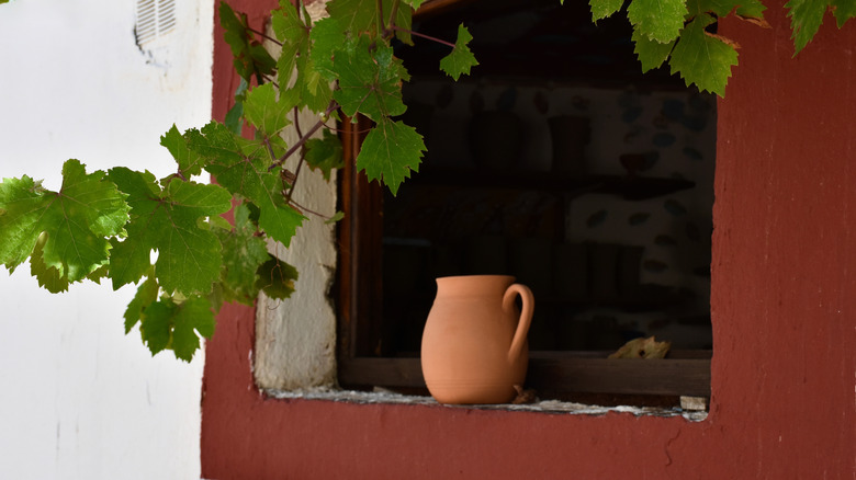 A clay jug resting on the sill of an unglazed window
