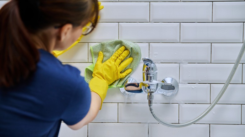 Woman cleaning a shower wall with a microfiber cloth.