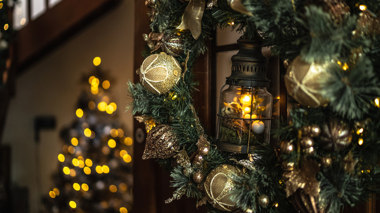 A holiday wreath hanging on an entryway door into a festively decorated home.