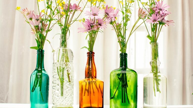 Colorful glass bottles holding cut flowers