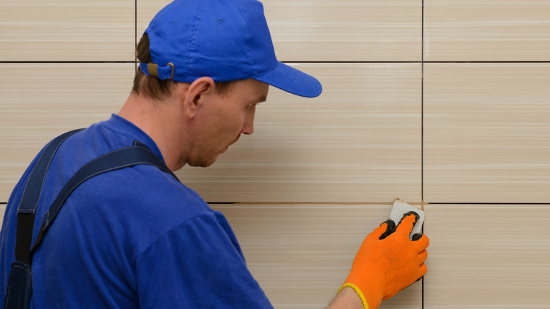 man adds grout to tiles