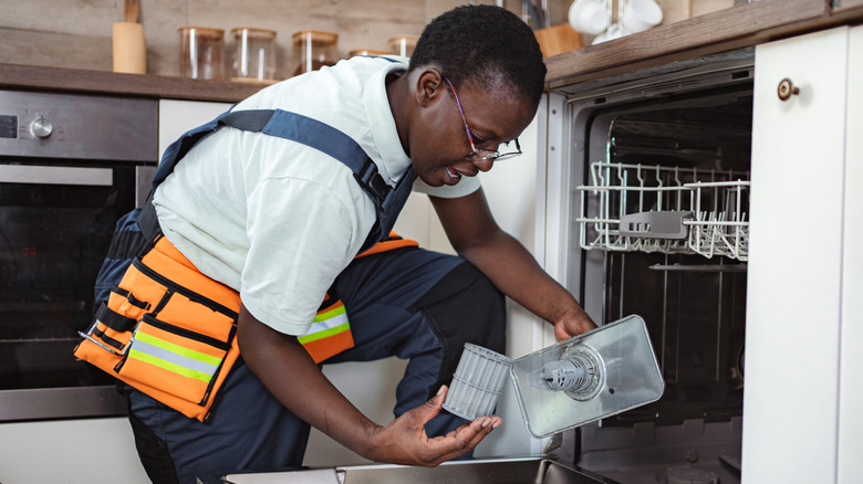 Repairman inspecting a dishwasher filter