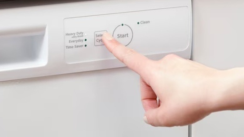 Person using the controls on a Hotpoint dishwasher