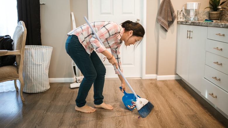 hunched woman sweeping floor