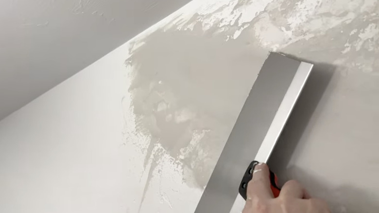 Smoothing out joint compound to hide a wall repair