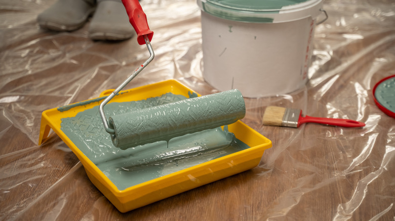 person dipping foam roller into paint tray