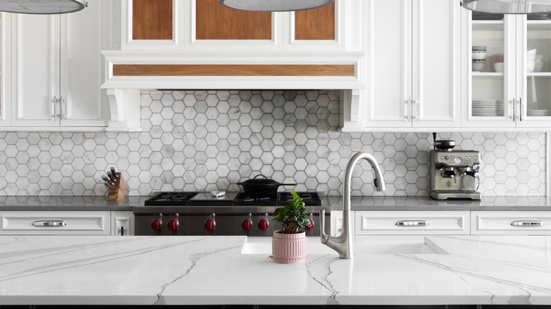 Full kitchen with marble island, white cabinets and stainless steel faucet