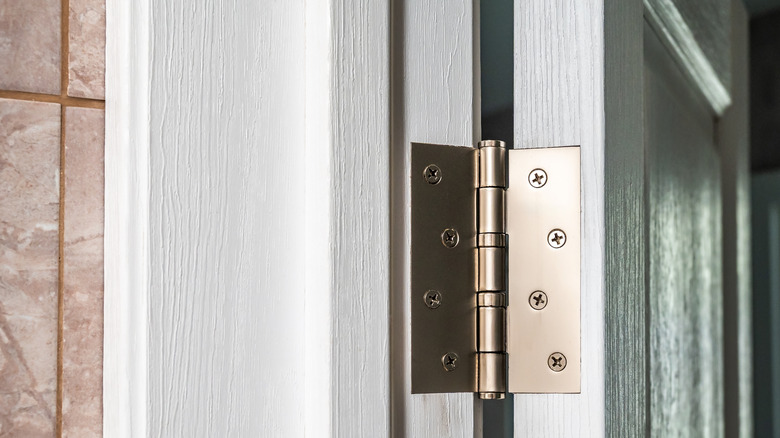 A white wooden door with metal hinges