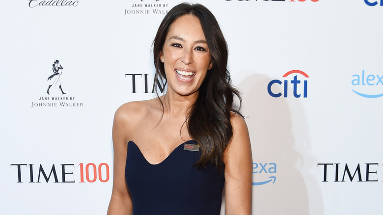 Joanna Gaines grinning in blue sleeveless dress on a red carpet