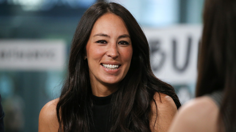 Joanna Gaines in black top smiling to the side of the camera