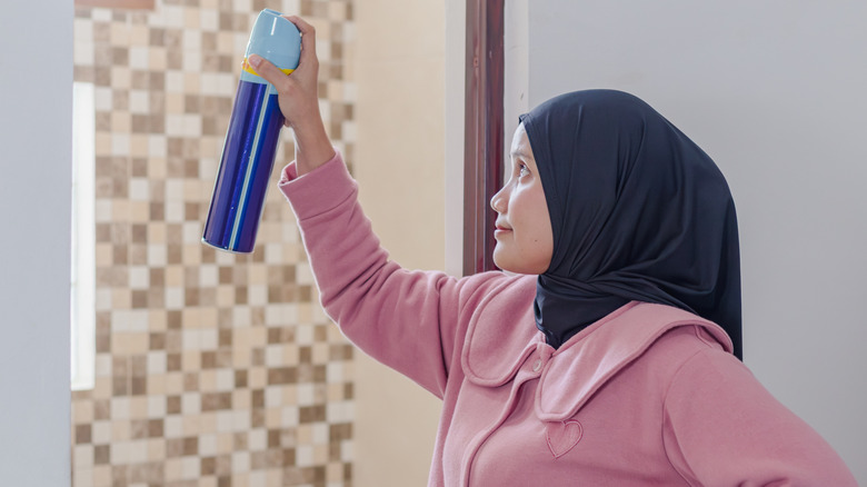 Woman holding aerosol air freshener