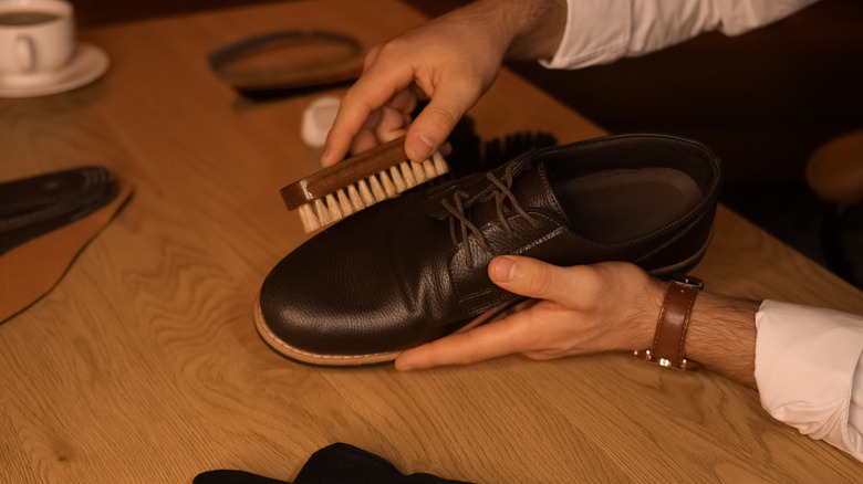 Man polishing shoe with brush in dark room
