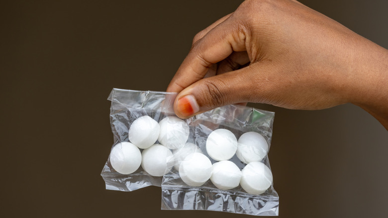 A female hand holding two mothball packets