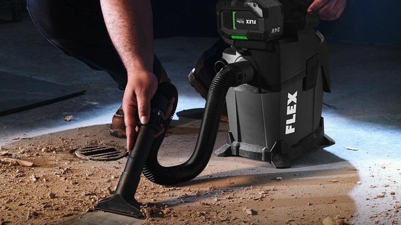 Person using Flex 24V 1.6 Gallon Wet/Dry Vacuum to clean construction debris