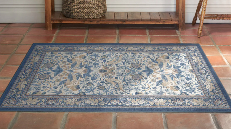A blue rug in the Morris & Co. Strawberry Thief pattern lays under a dining table and chairs