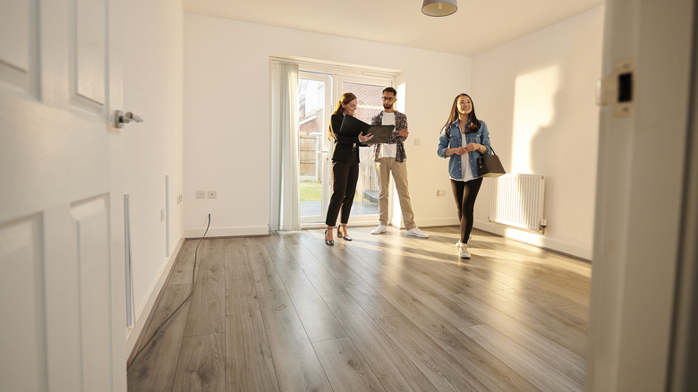 Couple viewing a home with gray-toned hardwood floors